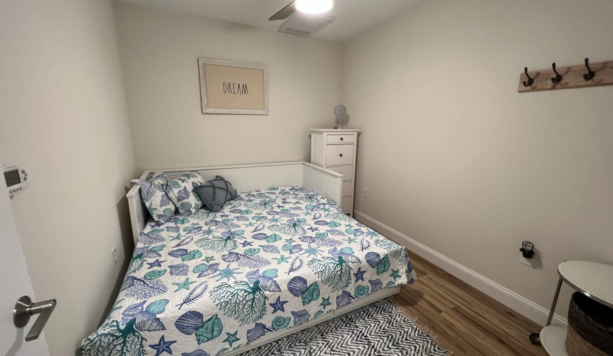 a bed room with a neatly made bed and a ceiling fan.