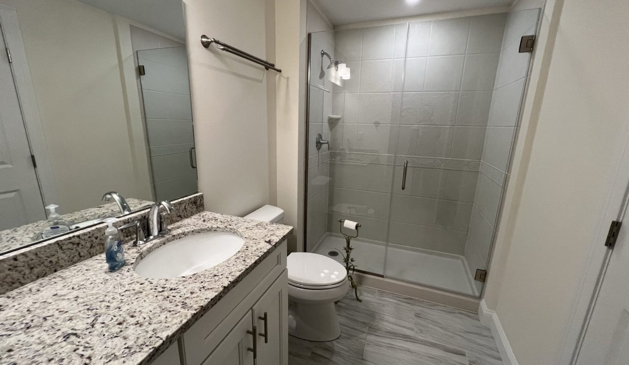 a bathroom with a sink, toilet, and shower.