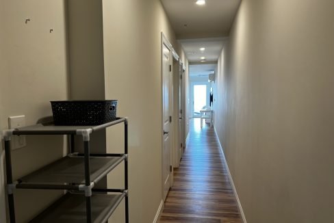 a long hallway with a shelf and a basket.