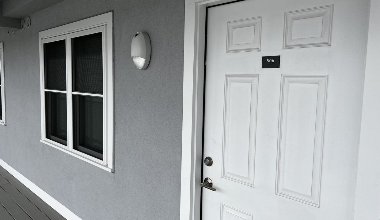 a white door and window on a gray house.