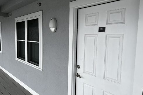 a white door and window on a gray house.