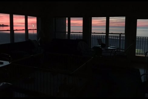 A living room with a view of the ocean and sunset.