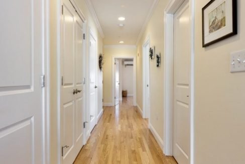 A hallway with white doors and hardwood floors.