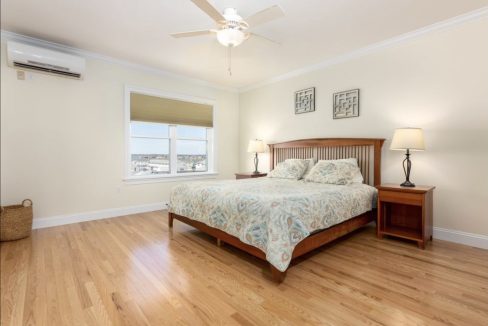 A bedroom with hardwood floors and a ceiling fan.
