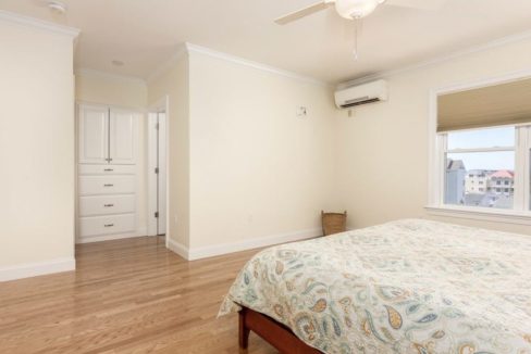 A bedroom with hardwood floors and a ceiling fan.