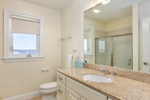A bathroom with granite counter tops and a window.