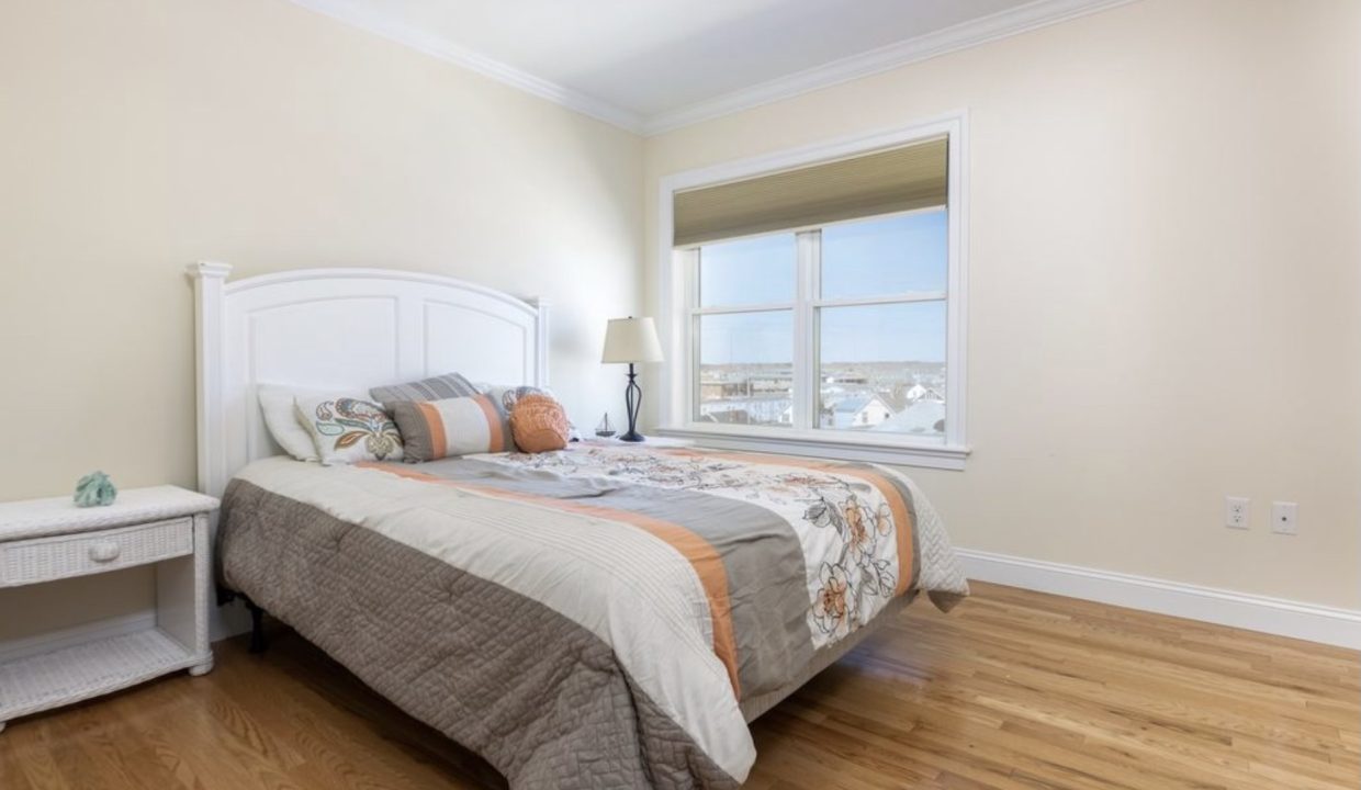 A bedroom with hardwood floors and a window.