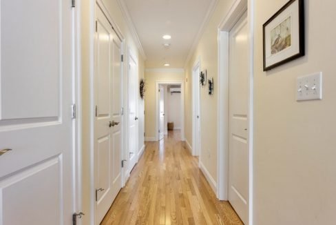 a long hallway with white doors and wood floors.
