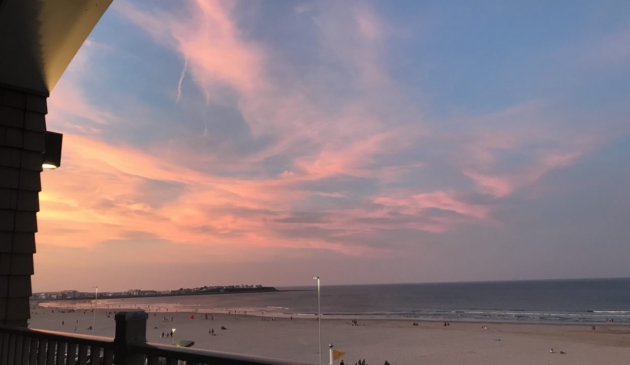 a view of a beach from a balcony at sunset.
