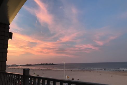 a view of a beach from a balcony at sunset.