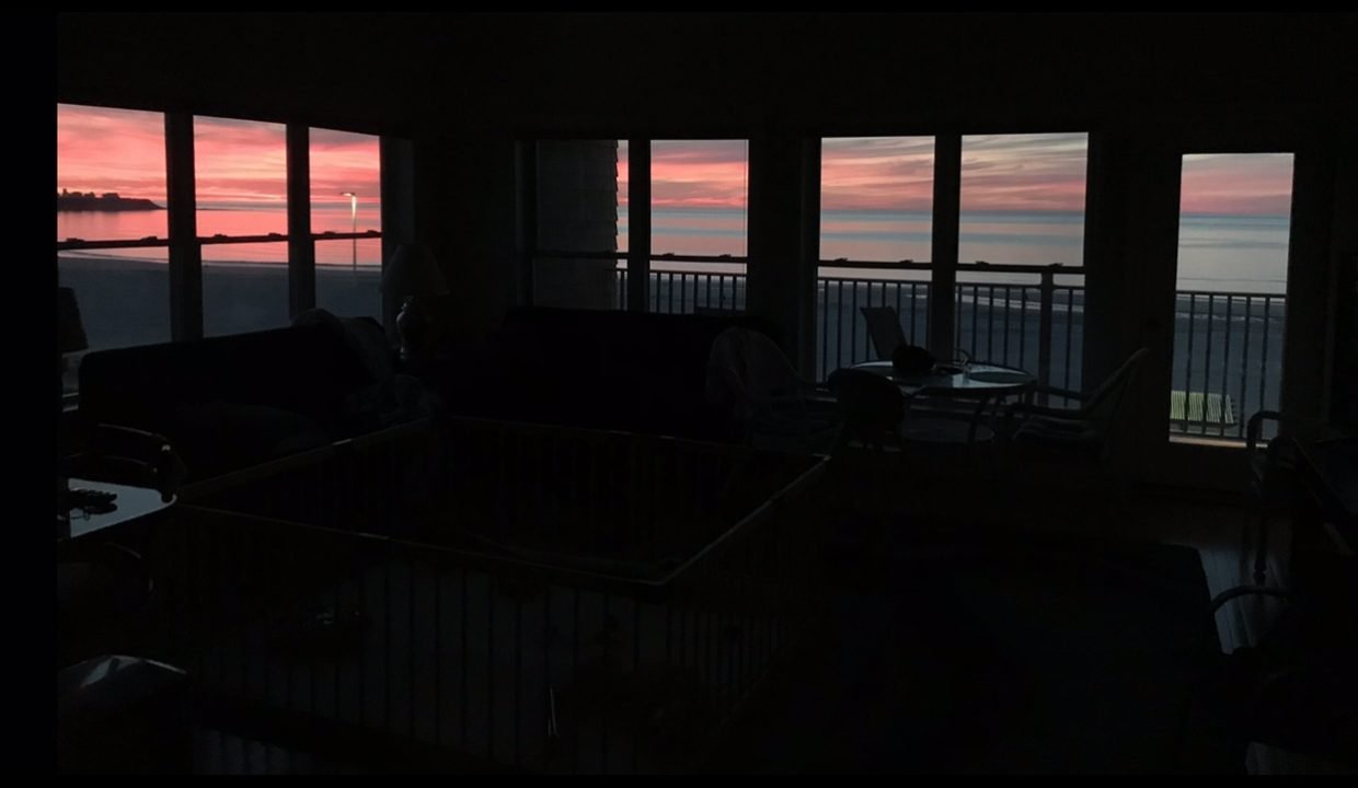 a living room filled with furniture and a view of the ocean.