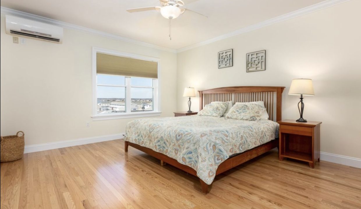 a bed room with a neatly made bed and a ceiling fan.