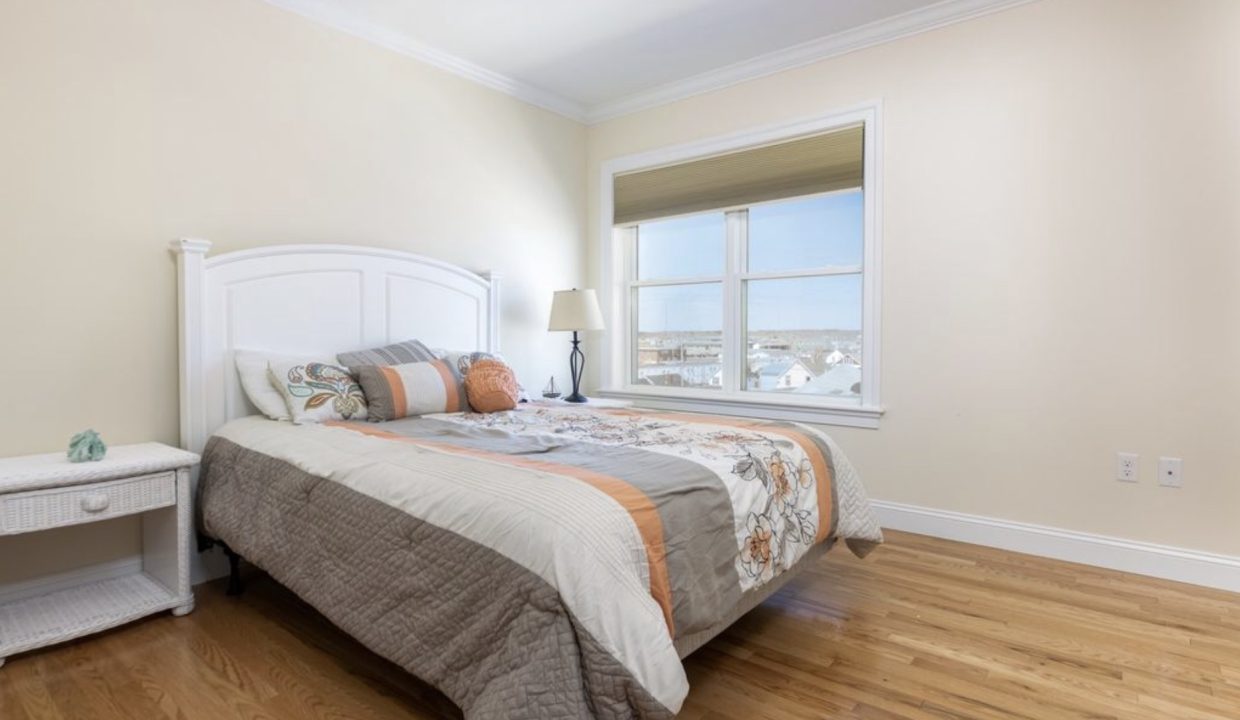 a bedroom with a bed, nightstand, and window.