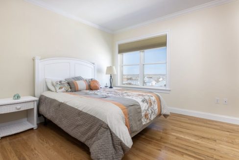 a bedroom with a bed, nightstand, and window.