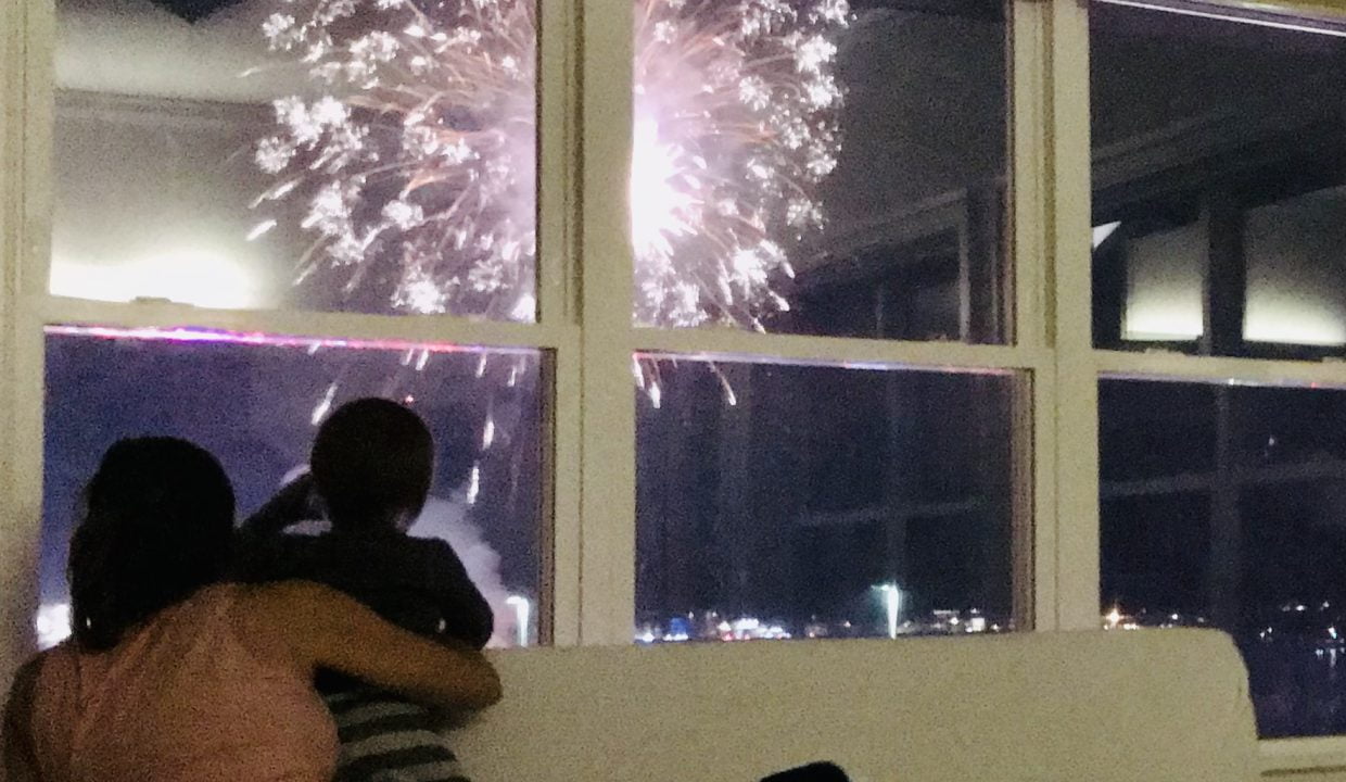 a group of people sitting on a couch watching fireworks.