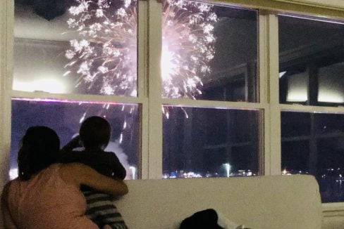 a group of people sitting on a couch watching fireworks.