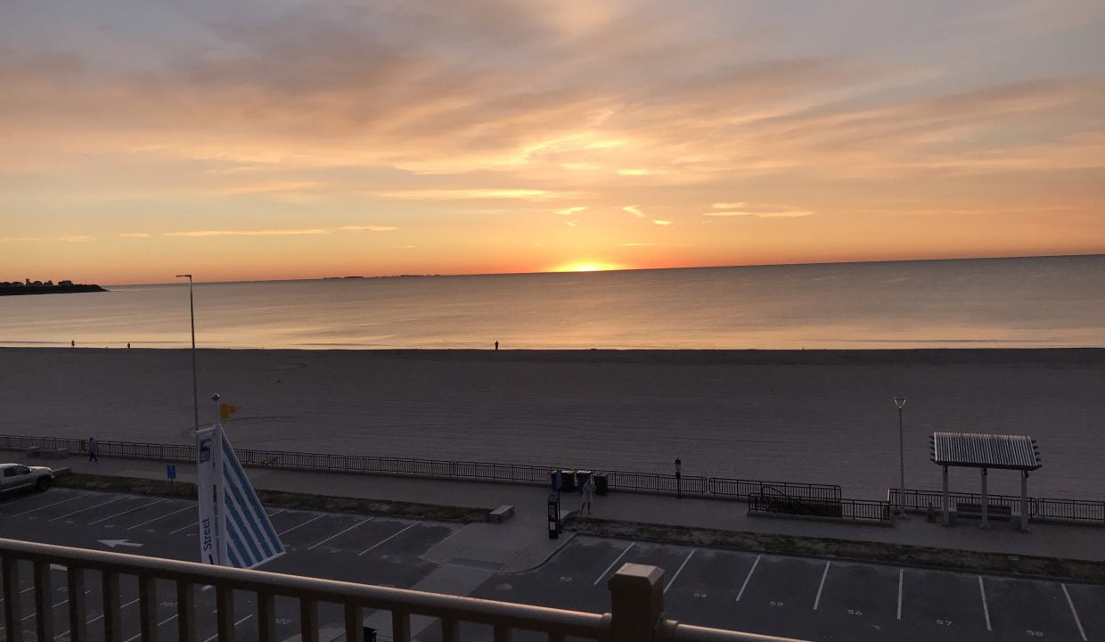 a view of a beach from a balcony at sunset.