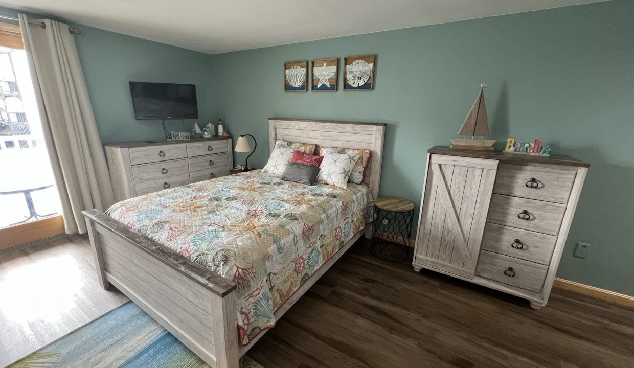 a bed room with a neatly made bed and a dresser.