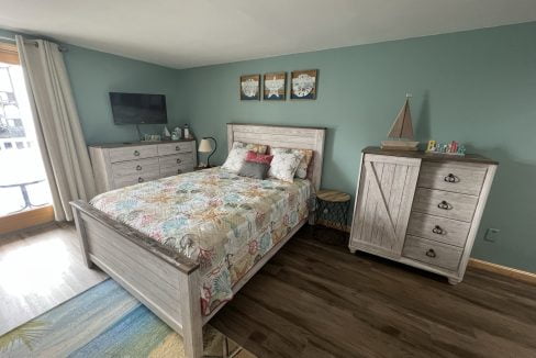 a bed room with a neatly made bed and a dresser.