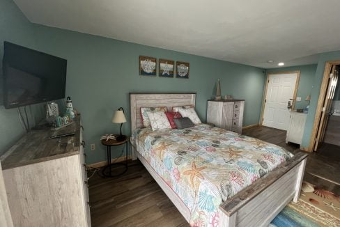 a bed room with a neatly made bed and a flat screen tv.