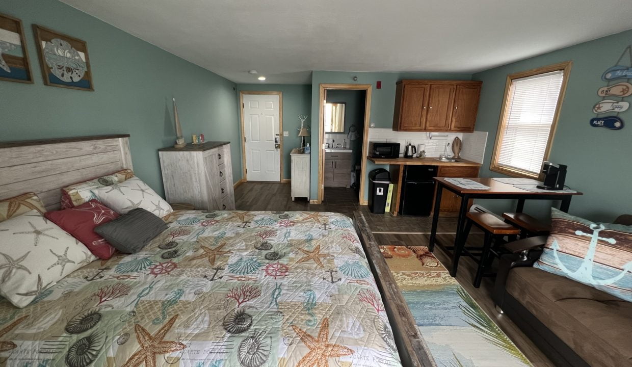 a bed sitting in a bedroom next to a kitchen.