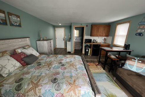 a bed sitting in a bedroom next to a kitchen.