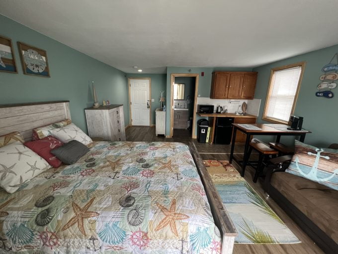 a bed sitting in a bedroom next to a kitchen.