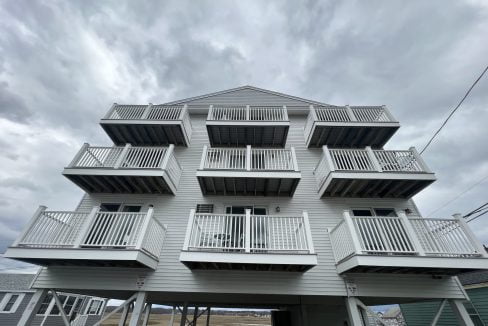 a tall white building with balconies on top of it.