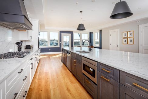 a large kitchen with a marble counter top and wooden floors.