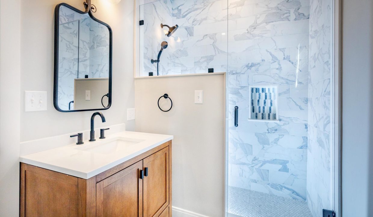 a bathroom with a sink, mirror and shower stall.