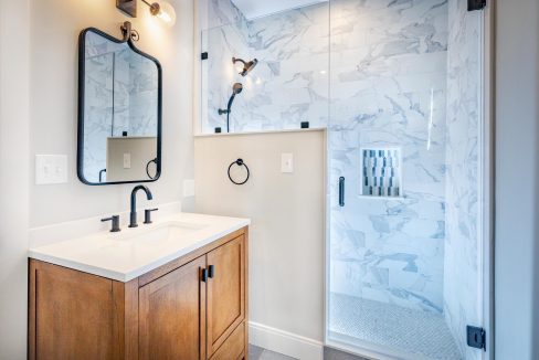 a bathroom with a sink, mirror and shower stall.