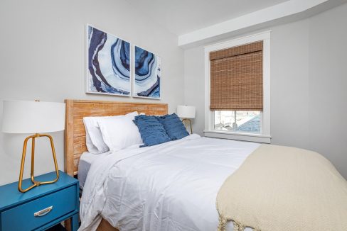 a bedroom with a white bed and blue nightstands.
