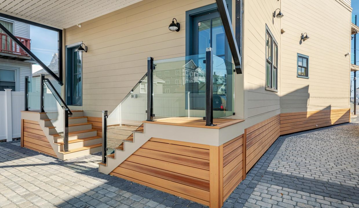 a house with a wooden staircase and glass railing.