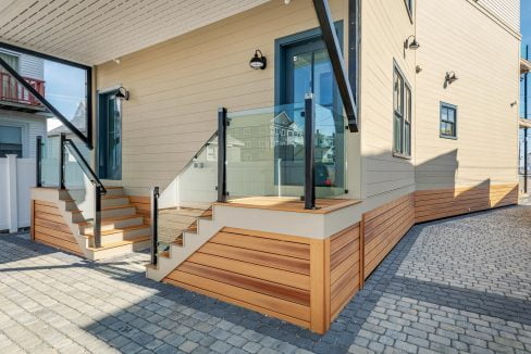 a house with a wooden staircase and glass railing.