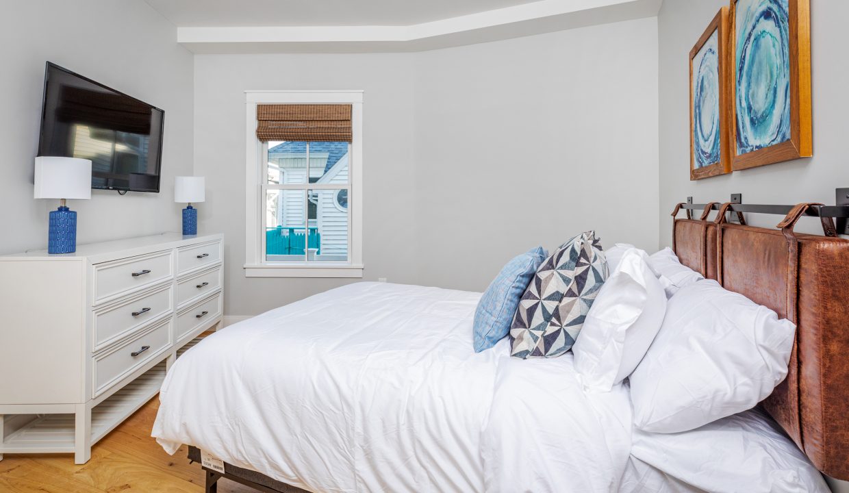 a bedroom with a bed, dresser and television.