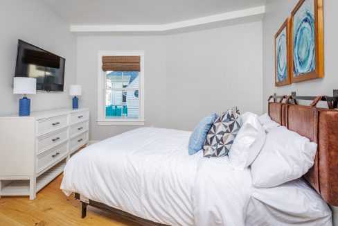 a bedroom with a bed, dresser and television.