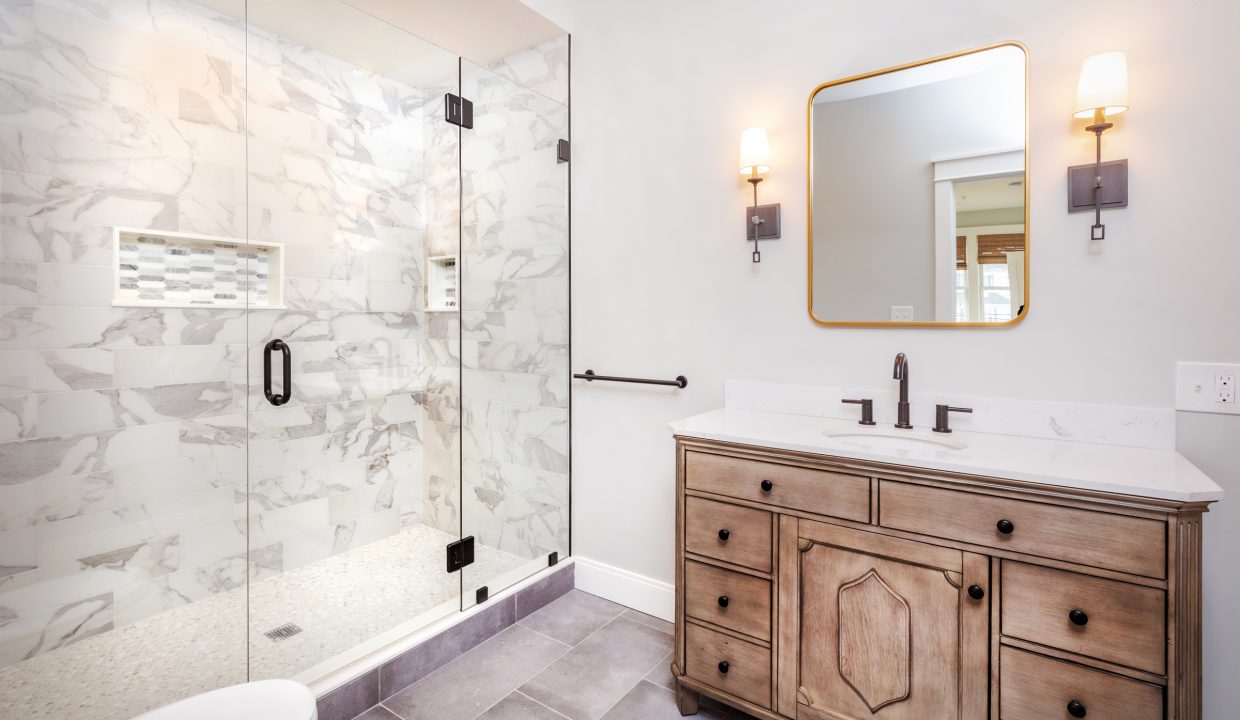 a bathroom with a sink, mirror, and shower.