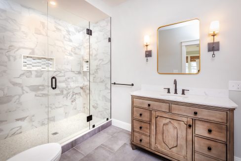 a bathroom with a sink, mirror, and shower.