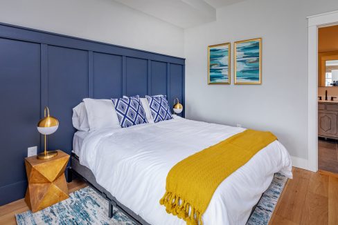 a bedroom with a blue headboard and a yellow blanket.