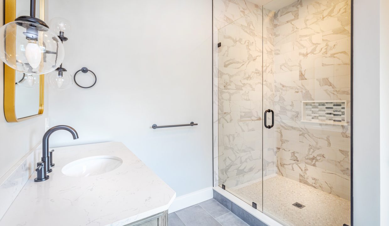 a bathroom with a walk in shower next to a sink.