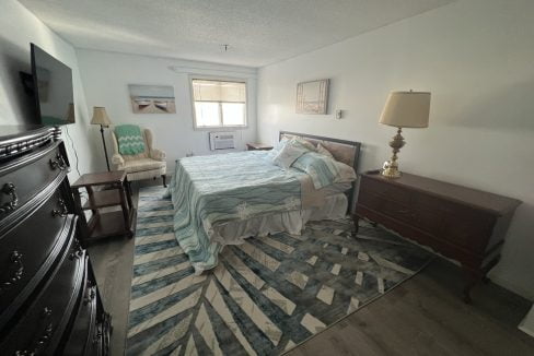 a bedroom with a bed, dresser and television.