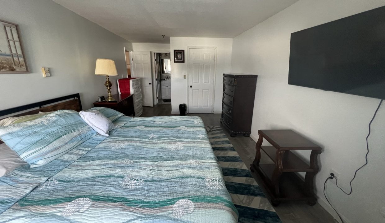 a bed room with a neatly made bed and a flat screen tv.