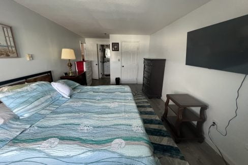 a bed room with a neatly made bed and a flat screen tv.