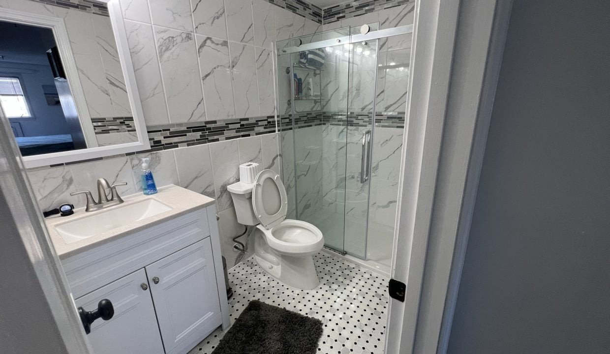 a bathroom with a toilet, sink, and shower.