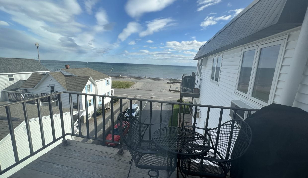 a balcony with a table and chairs and a view of the ocean.