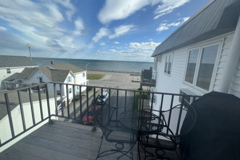 a balcony with a table and chairs and a view of the ocean.