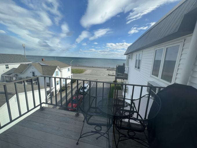 a balcony with a table and chairs and a view of the ocean.