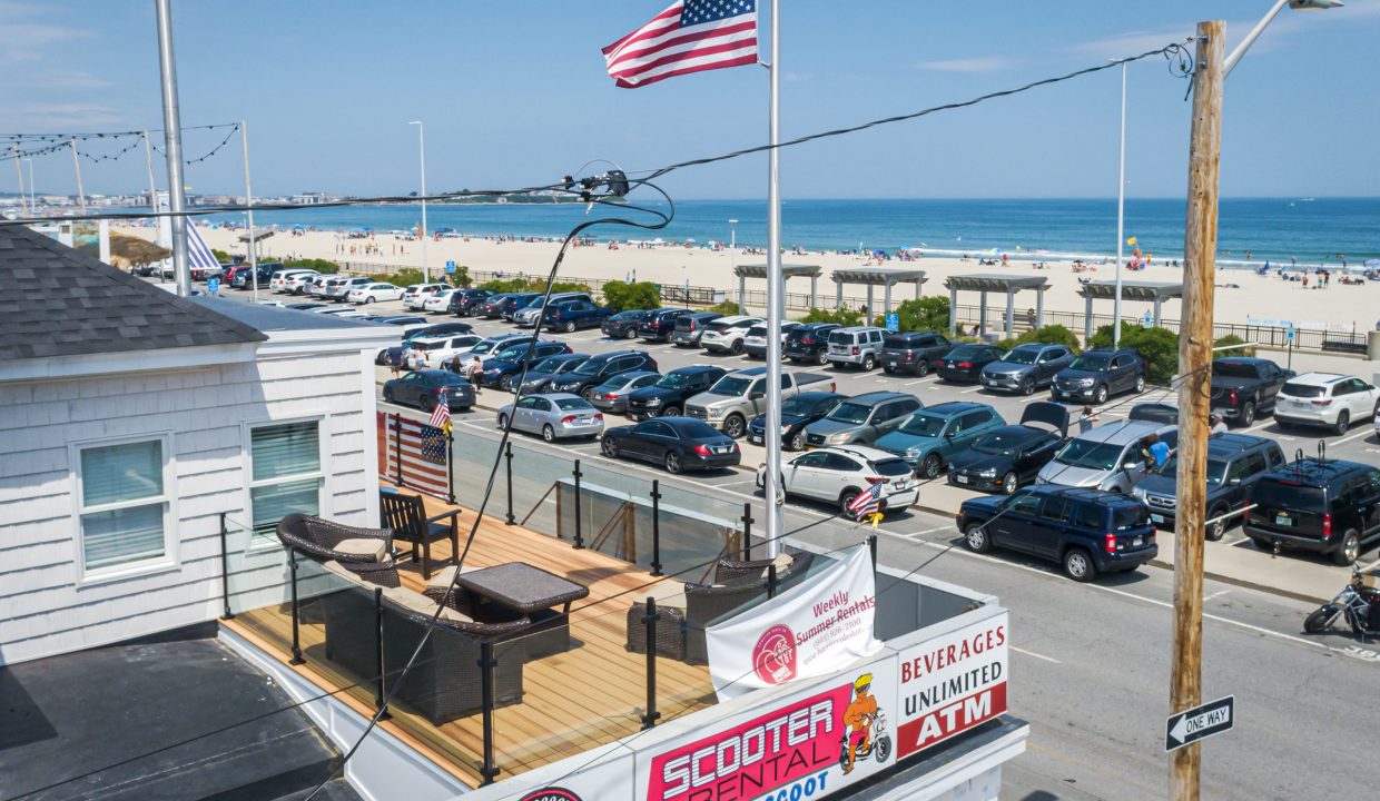 a parking lot full of parked cars next to a beach.