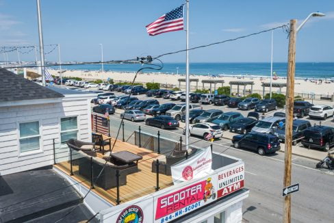 a parking lot full of parked cars next to a beach.