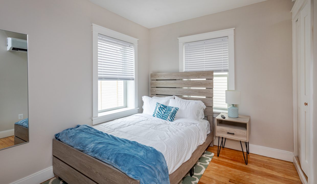 a bed sitting in a bedroom next to two windows.